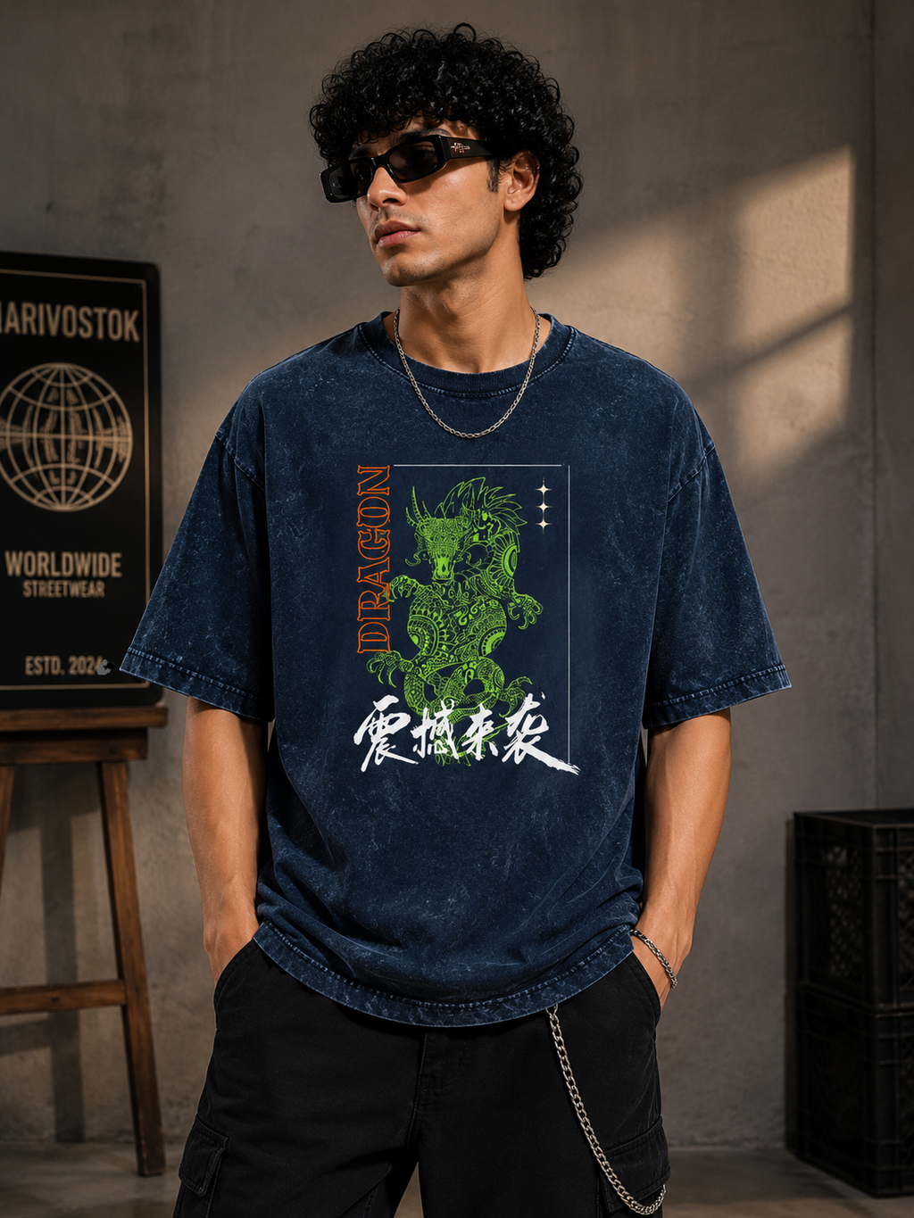 Man wearing a navy blue t-shirt with a dragon graphic and text, standing against a gray wall.