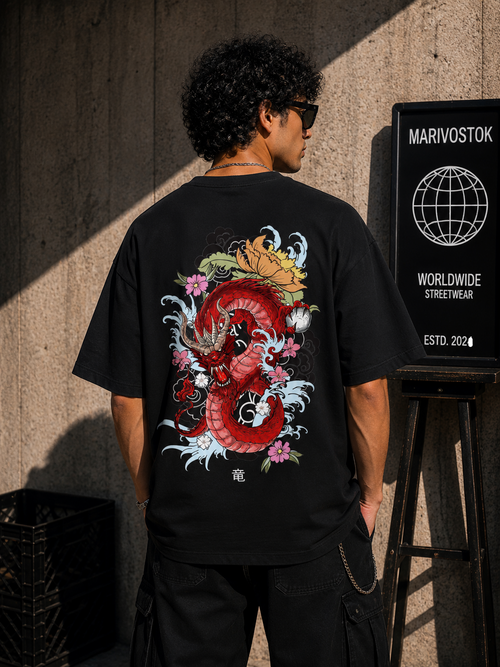 Person wearing a black t-shirt with a colorful dragon design, standing against a textured wall.