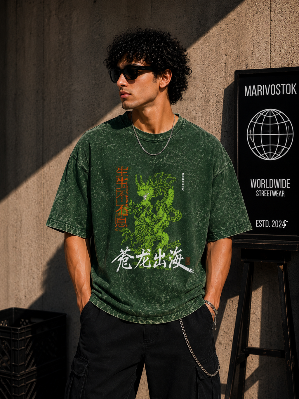 Person wearing a green t-shirt with a graphic design, standing against a textured wall with a brand sign.