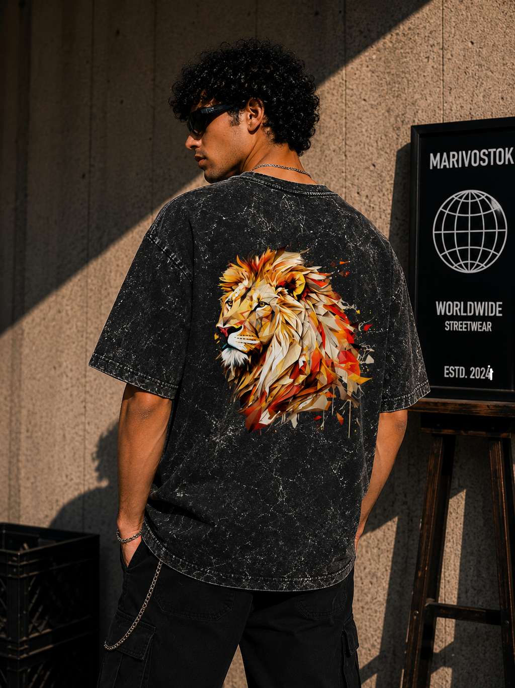 Person wearing a black t-shirt with a colorful lion design on the back, standing against a textured wall.