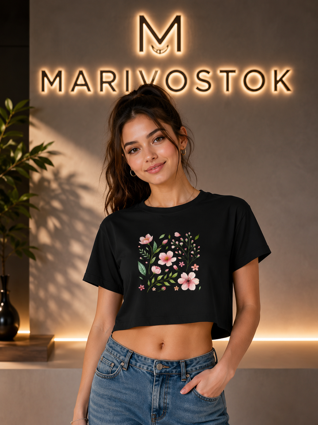Woman wearing a black t-shirt with floral design in front of a 'Marivostok' sign.